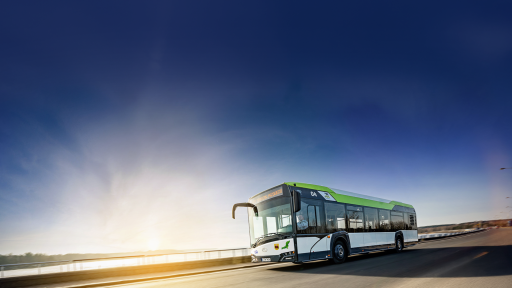 Na zdjęciu widoczny jest hybrydowy autobus MZK w ruchu, z charakterystycznym logo spółki